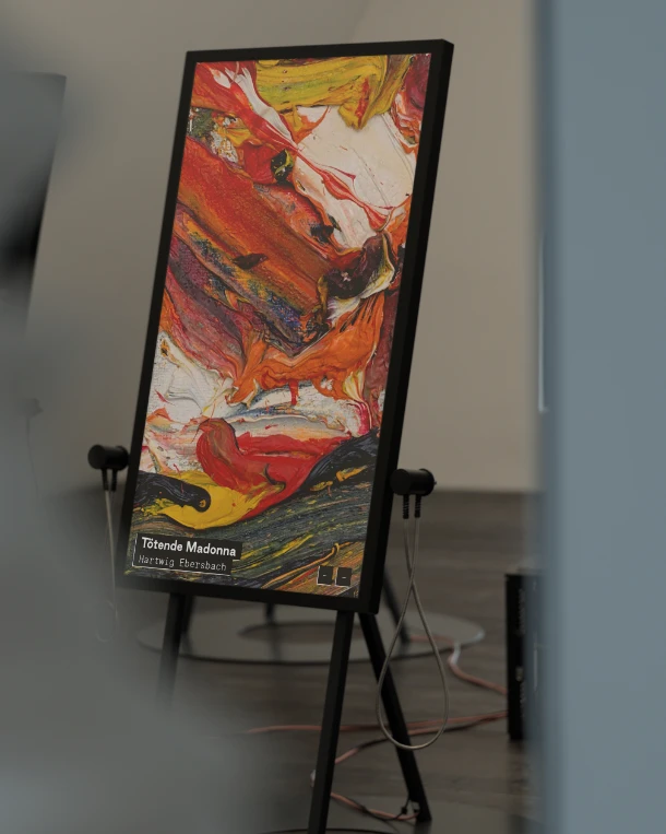 Digitales Display auf Staffelei zeigt das abstrakte Gemälde ‚Tötende Madonna‘ von Hartwig Ebersbach in einer Ausstellung des Kunstmuseums Magdeburg.